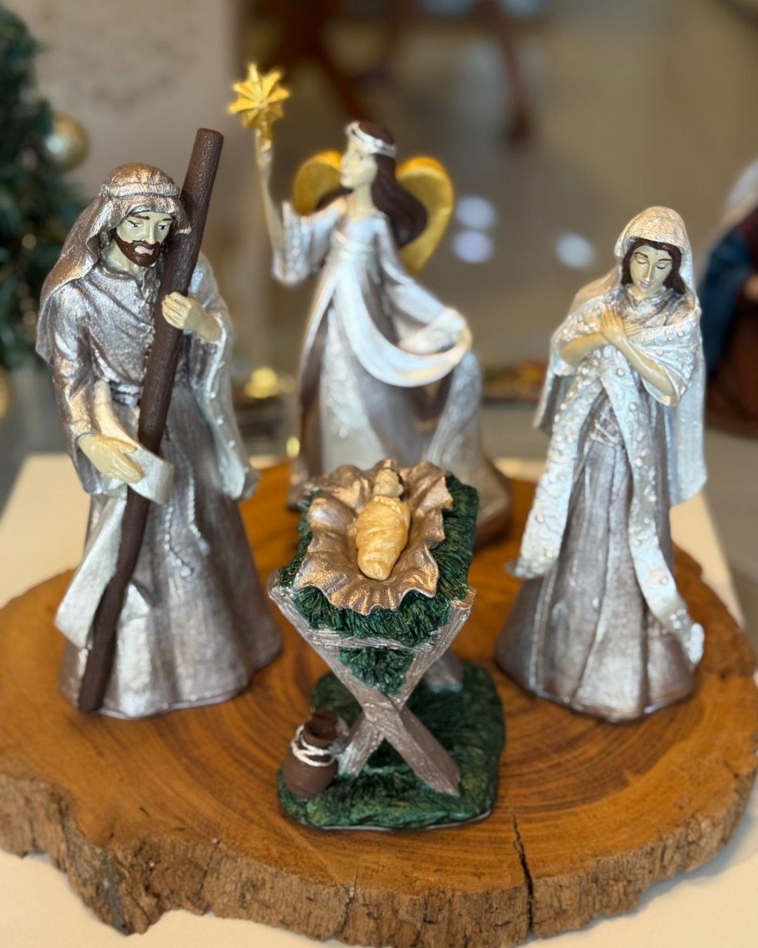 Conjunto de imagens sacras da Sagrada Família e um anjo com estrela sobre uma fatia de tronco de madeira.